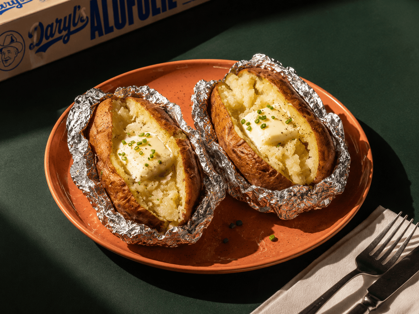 Foil-wrapped baked potatoes with the Daryl's Alufolie box in the background